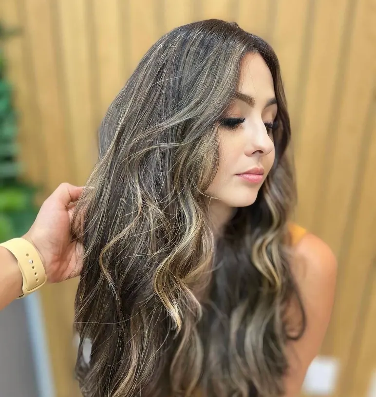 Morena com mechas iluminadas e ondas longas